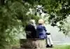 two people sitting on pavement facing on body of water